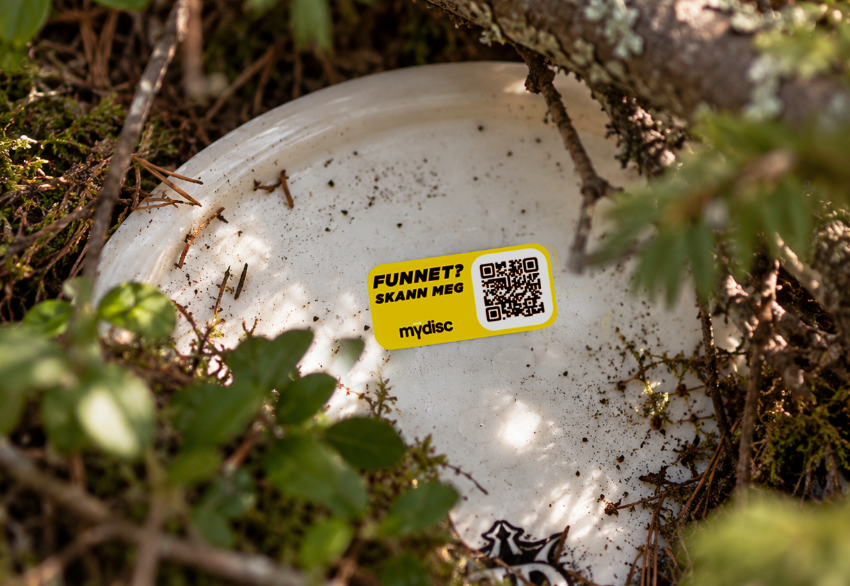 Hvit disc med gul ID-tag på skogbunnen